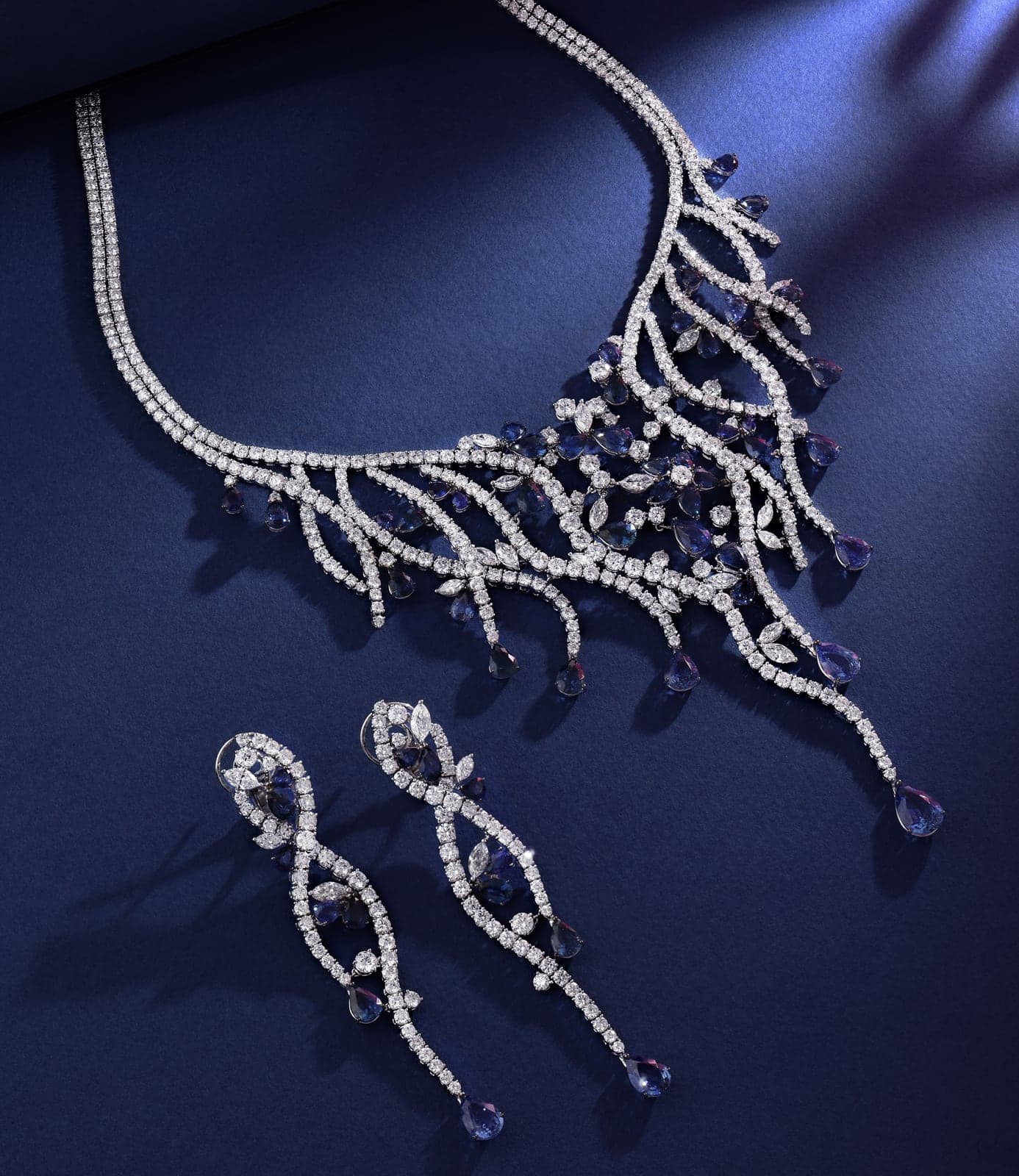 Sapphire and diamond necklace with matching drop earrings on deep blue
