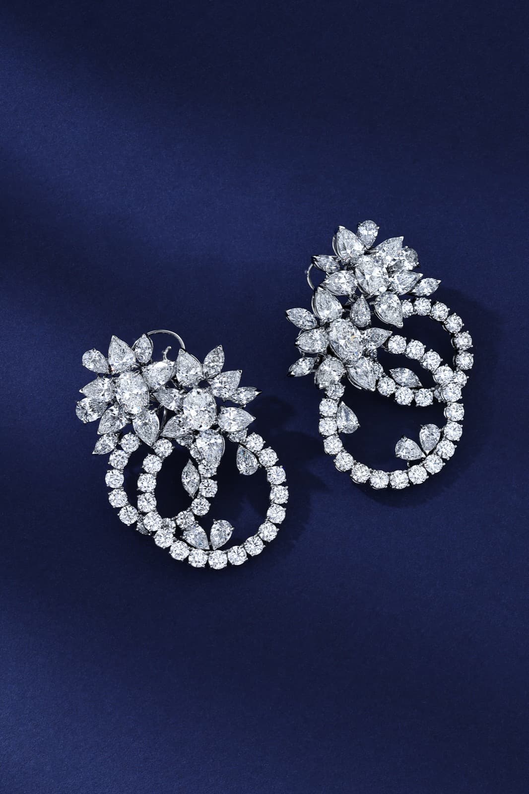 Pair of diamond cluster earrings on navy silk