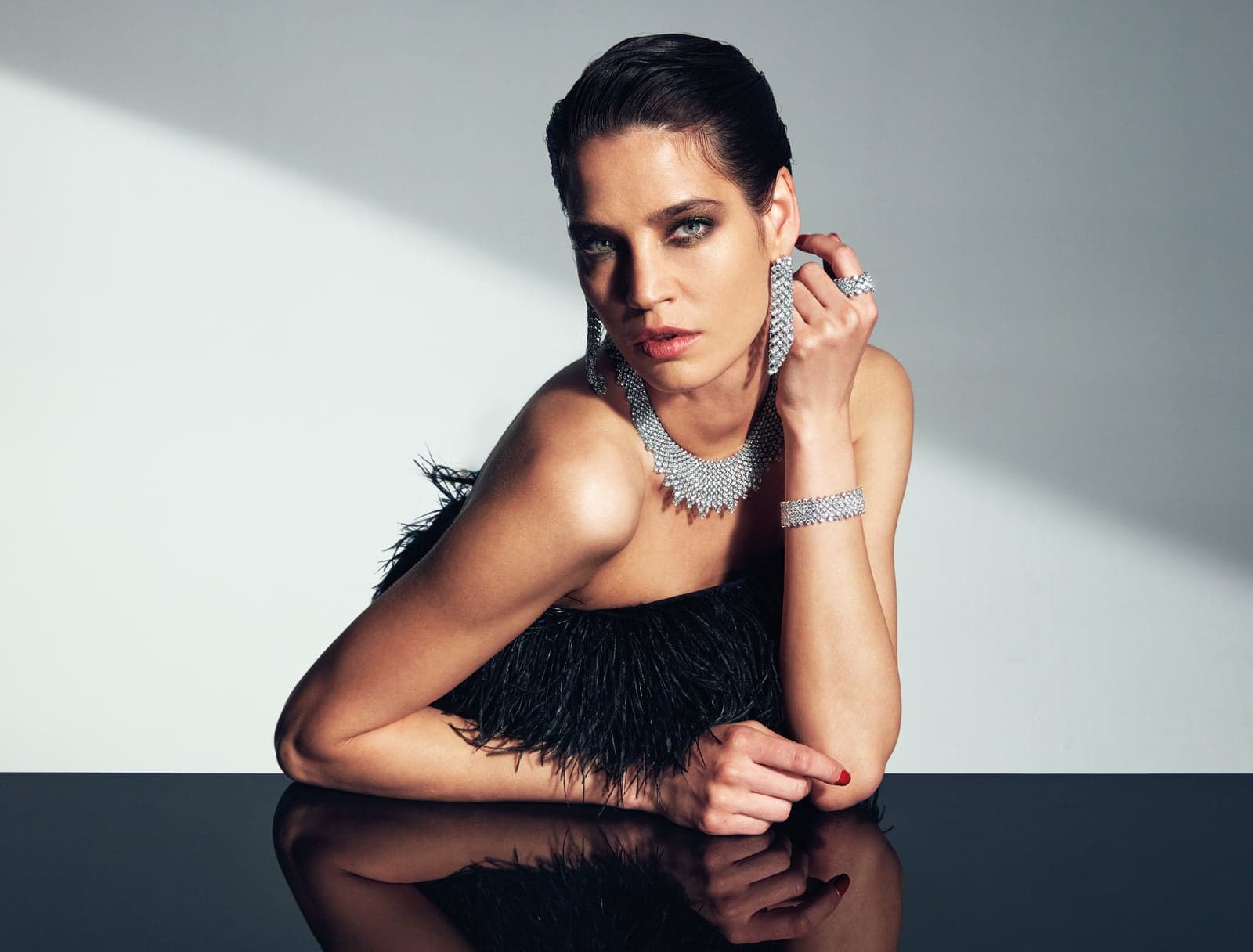 Diamond necklace, earrings and bracelets worn with a feathered black dress